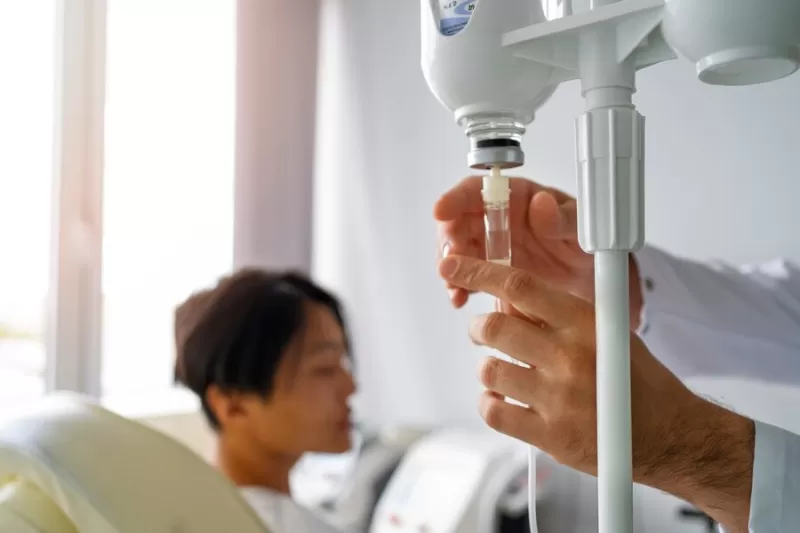 Cancer patient in a hospital, side view, undergoing intravenous fluid therapy